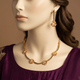 Gulraiz Emerald Green necklace set on an ivory mannequin in plum silk formalwear